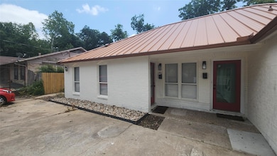 Doorway to property featuring a metal roof, brick