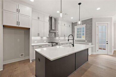 Kitchen featuring wall chimney exhaust hood, stainless steel gas range, a sink, baseboards, and light wood finished floors