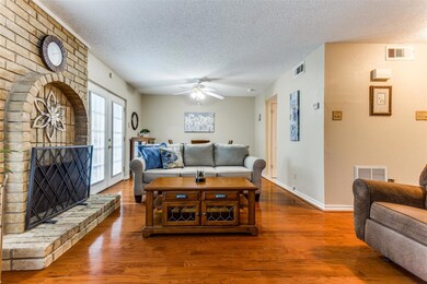 Living room featuring a brick fireplace, hardwood 