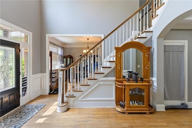 Foyer with arched walkways, a towering ceiling, hardwood floors, crown molding, and stairs