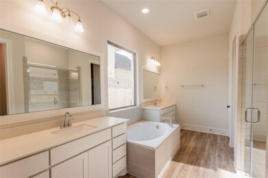This master bathroom is definitely move-in ready! Featuring a walk-in shower with tile surround, separate garden tub for soaking after a long day with custom tile detailing, light stained cabinets with light countertops, separate vanities, and a spacious walk-in closet with shelving.