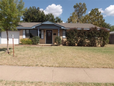 Ranch-style home featuring a porch, a front lawn, brick siding, and a garage
