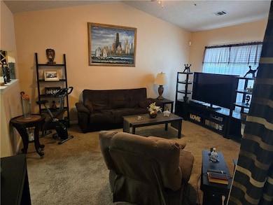 Living area with carpet floors and vaulted ceiling
