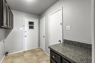 Laundry room with cabinets, light tile floors, and