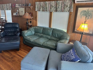 Living room featuring wood walls, wood finished floors, and an AC wall unit