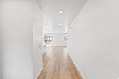 Corridor with light wood-type flooring and recessed lighting