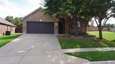 View of front of property featuring central air condition unit, a front yard, and a garage