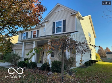 traditional home with covered porch, an attached garage, and a front yard