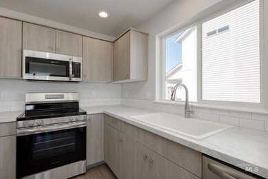 Kitchen with stainless steel appliances, light brown cabinets, and light countertops
