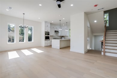 Unfurnished living room with healthy amount of natural light, recessed lighting, a chandelier, light wood-style flooring, and stairway