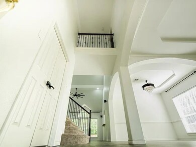 Stairway with a high ceiling, wood finished floors, plenty of natural light, and arched walkways