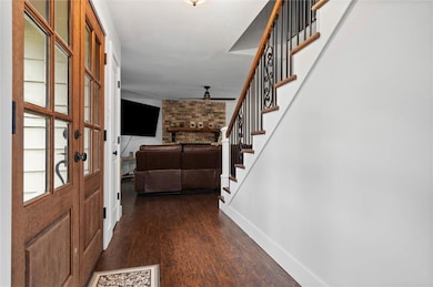 Foyer entrance with a ceiling fan, stairway, and dark wood finished floors
