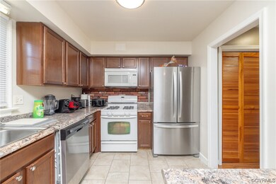 Kitchen with light stone counters, backsplash, light tile floors, and appliances with stainless steel finishes