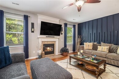 Living room with ceiling fan, wood finished floors, and a tile fireplace