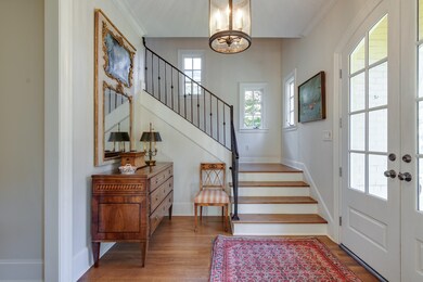 Foyer featuring wood finished floors, stairway, crown molding, a chandelier, and french doors