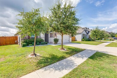 View of property hidden behind natural elements with concrete driveway, a garage, and brick siding