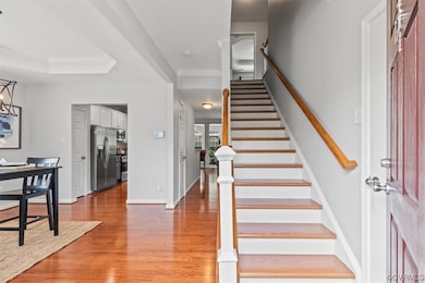 Staircase with crown molding, light hardwood flooring, and a tray ceiling
