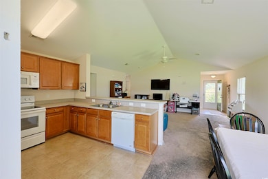 Kitchen with white appliances, ceiling fan, a peninsula, light countertops, and open floor plan