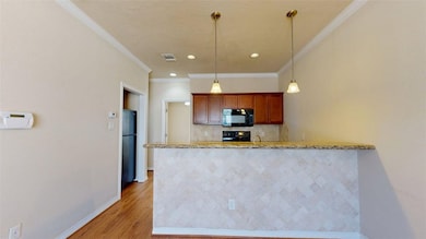 Kitchen with black appliances, a peninsula, pendan