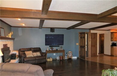 Family room with beams and gas fireplace, open to kitchen.