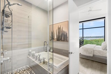 Bathroom featuring ensuite bathroom, a water view, a shower stall, a garden tub, and ceiling fan