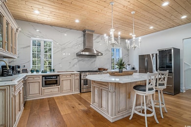Kitchen featuring wall chimney range hood, stainless steel appliances, wood ceiling, light wood-style flooring, and recessed lighting