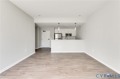 Unfurnished living room with light wood-type flooring and baseboards