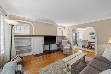 Hardwood floored living room featuring crown molding and ceiling fan