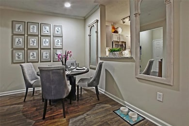 Dining area with dark wood-type flooring, crown molding, and rail lighting
