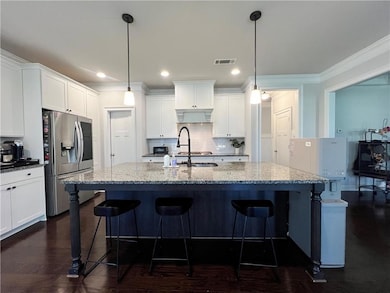 Kitchen with stainless steel fridge with ice dispenser, backsplash, white cabinetry, a kitchen breakfast bar, and crown molding