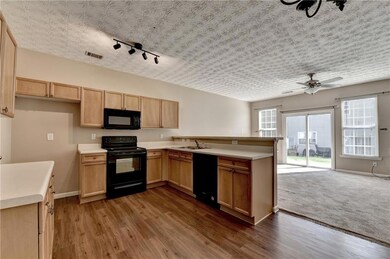 Kitchen featuring black appliances, a peninsula, light countertops, ceiling fan, and open floor plan