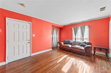 Living area featuring hardwood / wood-style flooring, baseboards, and crown molding