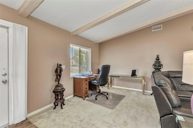 Living room with carpet and tile flooring, cathedral ceilings with accent wood beams.