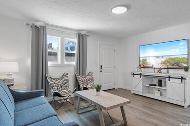 Living area featuring light wood-style floors and a textured ceiling