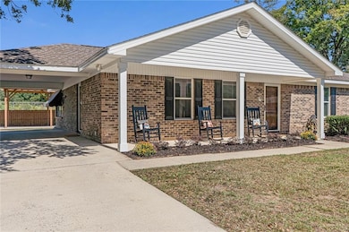Single story home featuring a front lawn, brick siding, covered porch, and concrete driveway
