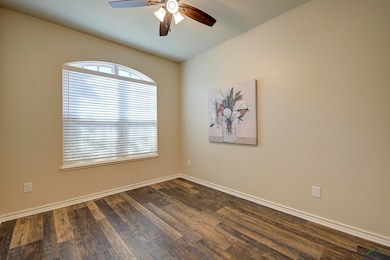 Empty room featuring ceiling fan, dark wood finish