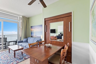 Dining room with a textured ceiling, a water view, ceiling fan, wainscoting, and tile patterned floors
