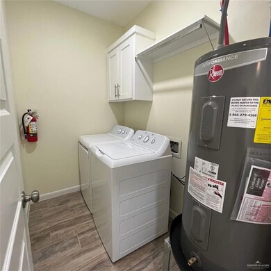 Washroom with water heater, separate washer and dryer, cabinet space, and dark wood-style floors