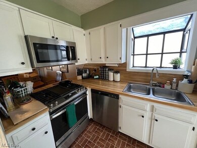Kitchen with appliances with stainless steel finishes, a textured ceiling, sink, and white cabinets