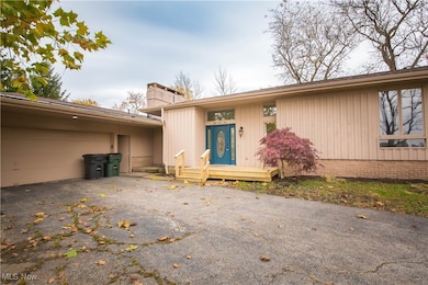 Entrance to property featuring a chimney, asphalt driveway, an attached garage, and a deck
