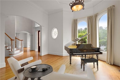 Living area featuring arched walkways, stairs, ornamental molding, light wood-type flooring, and decorative columns