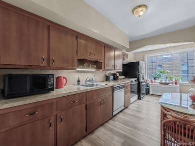 Kitchen with white appliances, backsplash, radiator heating unit, light countertops, and open shelves