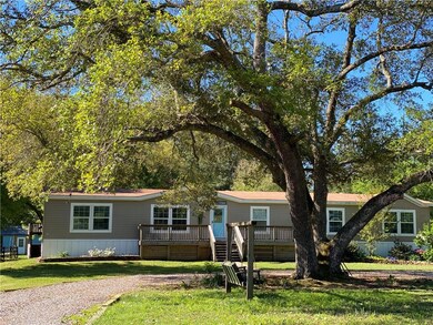 Front of Mobil home with large oak in front.