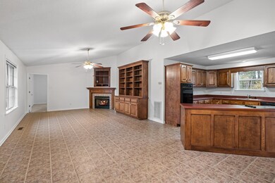 Kitchen opens to a large den with vaulted ceilings, custom built-ins, and a ventless gas fireplace that is in working order.