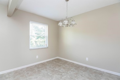 Unfurnished room with a chandelier and baseboards
