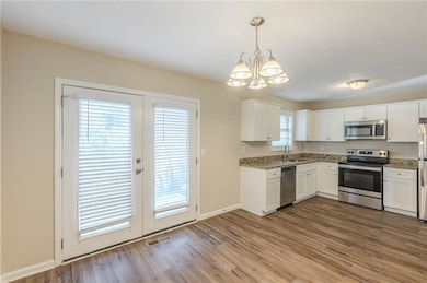 Kitchen with visible vents, appliances with stainless steel finishes, dark wood-type flooring, white cabinets, and a sink