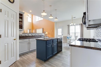 Kitchen featuring tasteful backsplash, an island with sink, blue cabinets, white cabinets, and dishwasher