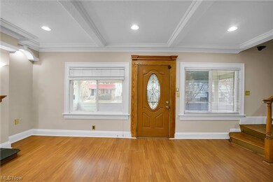 Foyer featuring light wood-type flooring, beam ceiling, and crown molding