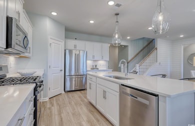 Kitchen featuring appliances with stainless steel finishes, light countertops, a center island with sink, and recessed lighting