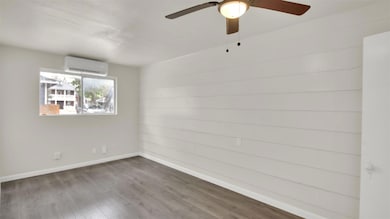 Spare room with wood finished floors, a ceiling fan, and an AC wall unit